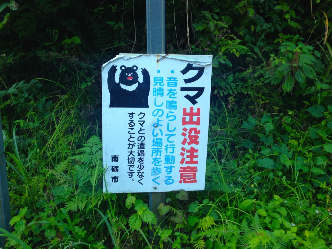 Warning sign for bears in Japanese forest.